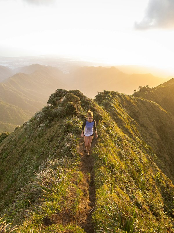 A woman walking along a hilltop path at golden hour