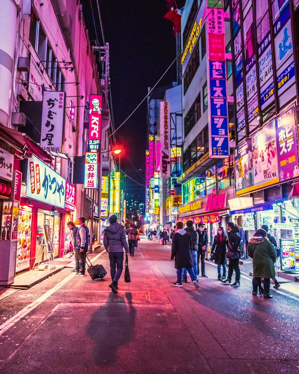 People walking down a neon-lit street in Tokyo